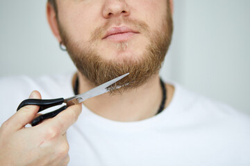 Close-Up of a Young Man Trimming His Beard With Scissors Indoors