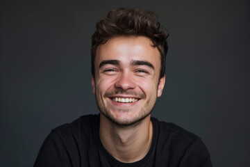 Obraz premium A young man with a beard is smiling and wearing a black shirt