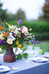 Bouquet of pink, violet and yellow flowers on a table set for dinner