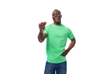 young handsome african man in light green t-shirt and jeans holding credit card with mockup