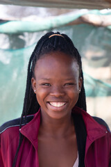 Fototapeta premium village smiling african social worker young woman with braids standing in the yard