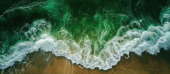 Aerial view of green water and shallow waves on the beach.