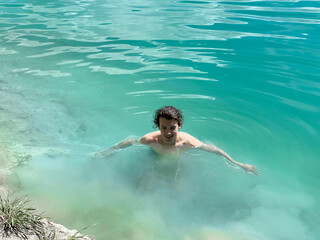 Young guy bathing in turquoise blue water.