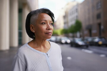 Fototapeta premium older woman in city street, sad thoughtful expression