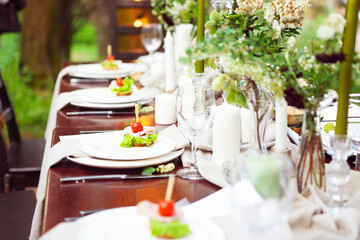 Decoration of wedding table with crystal vases, flowers in botanical style in the garden