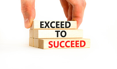 Exceed to succeed symbol. Concept words Exceed to succeed on beautiful wooden blocks. Beautiful white table white background. Businessman hand. Business and exceed to succeed concept. Copy space.