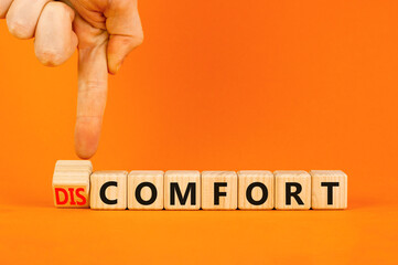 From discomfort to comfort symbol. Concept word Discomfort or Comfort on wooden cubes. Beautiful orange background. Businessman hand. Business and from discomfort to comfort concept. Copy space.