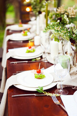 Decoration of wedding table with crystal vases, flowers and appetizer