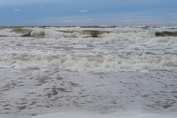 seashore on a cloudy day, strong waves, storm on the horizon, dark blue sky