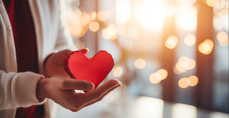 Happy Valentine's Day! A woman holds a red heart in her hands in a cozy bright house. Photo for background or banner - obrazy, fototapety, plakaty