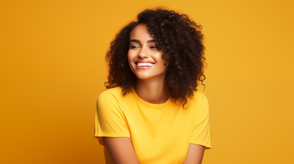 Portret studyjny młodej kobiety uśmiechniętej na żółtym tle z dużą ilością wolnego tła - obrazy, fototapety, plakaty