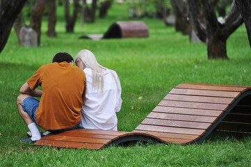 Fototapeta premium a young couple is sitting on a bench in a green garden