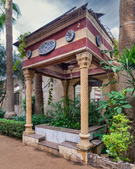 Charming stone gazebo with carved columns nestled amidst lush greenery in a serene urban garden