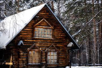 An old wooden two-storey house under the snow on a winter day.