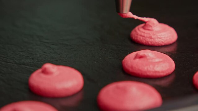 Making pink macaroons. Confectioner extruding macaron dessert. Baking concept. Making French dessert. Close-up in 4K, UHD
