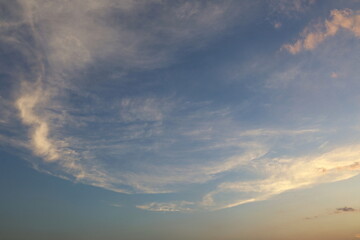 White circular clouds in the sky. Thin clouds with beautiful arches fill the blue sunset sky in soft focus.