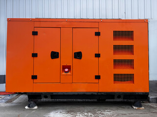 Orange coloured generator on the edge of a workplace.