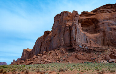 Fototapeta premium Desert landscape with red rocks and dry vegetation on red sands in Monument Valley, Navajo Nation, Arizona - Utah