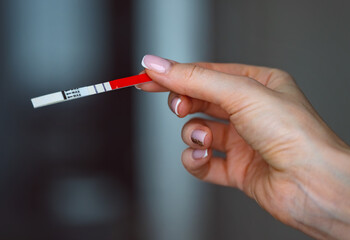 Woman hand holding positive pregnancy test with two lines on it. Pregnancy or fertility concept....