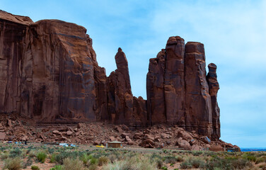 Fototapeta premium Desert landscape with red rocks and dry vegetation on red sands in Monument Valley, Navajo Nation, Arizona - Utah