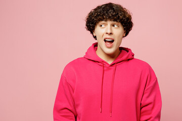 Young shocked amazed surprised Caucasian man he wears hoody casual clothes look aside on area with opened mouth isolated on plain pastel light pink color background studio portrait. Lifestyle concept.