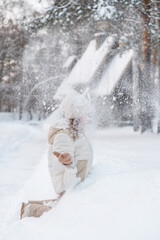 A girl throws snow up in winter.
