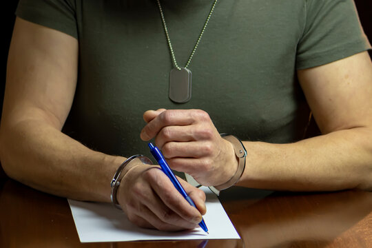 Handcuffed military soldier signs statement for investigation, interrogation of serviceman.