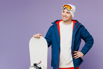 Smiling man wears warm blue windbreaker jacket ski goggles mask hat hold snowboard look aside on...