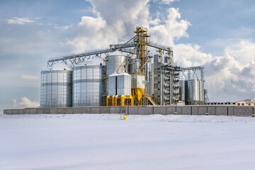 Obraz premium silos and agro-processing plant for processing for drying cleaning and storage and seed preparation complex in snow of winter field