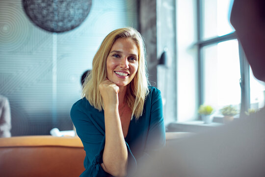 Young smiling businesswoman talking to colleague in office