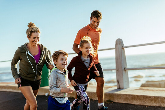 Young family jogging together by the ocean - Powered by Adobe
