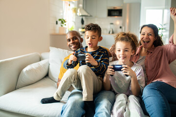 Young children playing video games with parents watching at home