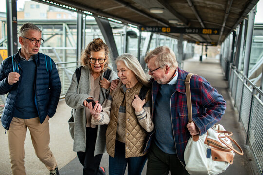 Group of senior people using smartphone at train station