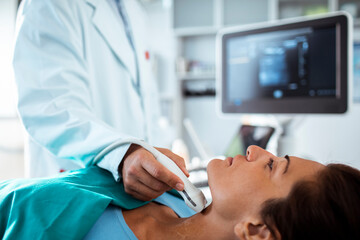 Doctor performing thyroid ultrasound examination on female patient
