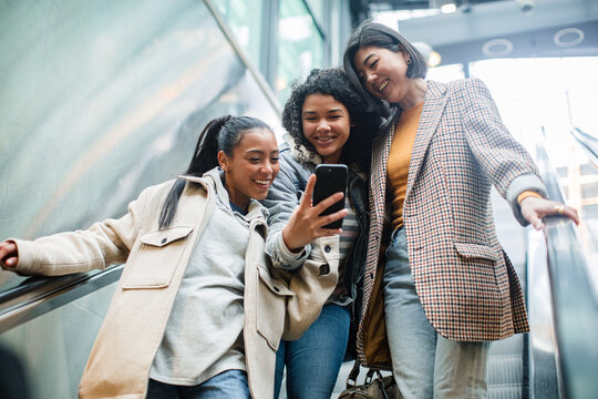 Young women using smartphone on escalator