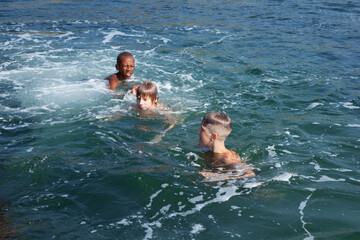 Children swim in the sea during summer holidays - 714839617