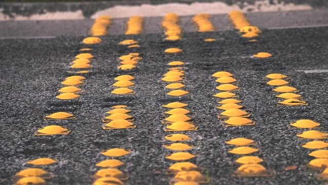 Time lapse close up of yellow semi sphere road studs or speed bump at night on asphalt road. Many cars passing fast by traffic speed control system