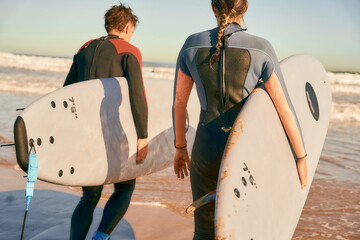 Back view of surfers with surfboards in wetsuit entering towards ocean for surfing on waves - obrazy, fototapety, plakaty