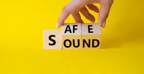 Safe and Sound symbol. Businessman hand Turns cubes with words Safe and Sound. Beautiful yellow background. Business and Safe and Sound concept. Copy space