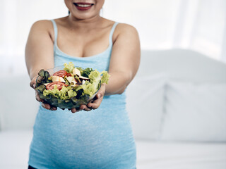 Maternity in Comfort: Asian Woman Eating Nutritious slad in Homely Bedroom