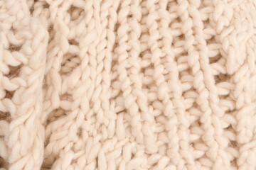 A fragment of beige knitted fabric, knitted from white sheep wool.