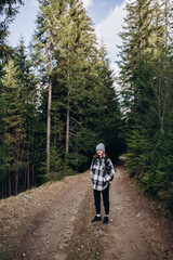 Fototapeta premium a beautiful girl in a checkered shirt travels in the mountains. overcome the route in the mountains with a backpack. autumn landscapes. Carpathians 