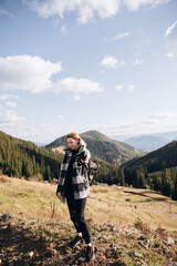 Fototapeta na wymiar a beautiful girl in a checkered shirt travels in the mountains. overcome the route in the mountains with a backpack. autumn landscapes. Carpathians