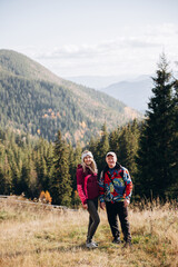 family young couple in the mountains, autumn forest. a man and a woman went to the mountains. clothes and shoes for trekking. Man and a woman went on a mountain trip. CARPATHIAN MOUNTAINS