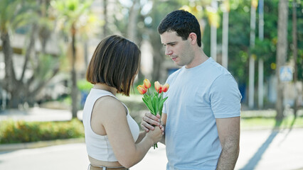 Beautiful couple surprise with bouquet of flowers standing together at street