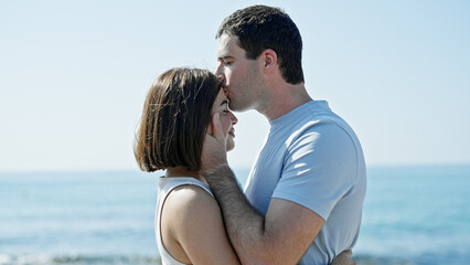 Beautiful couple standing together kissing at seaside