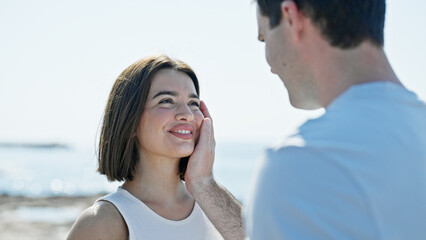 Fototapeta premium Beautiful couple standing together looking each other touching face at seaside