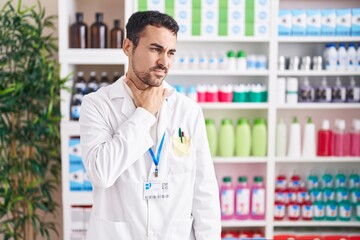 Handsome hispanic man working at pharmacy drugstore touching painful neck, sore throat for flu, clod and infection