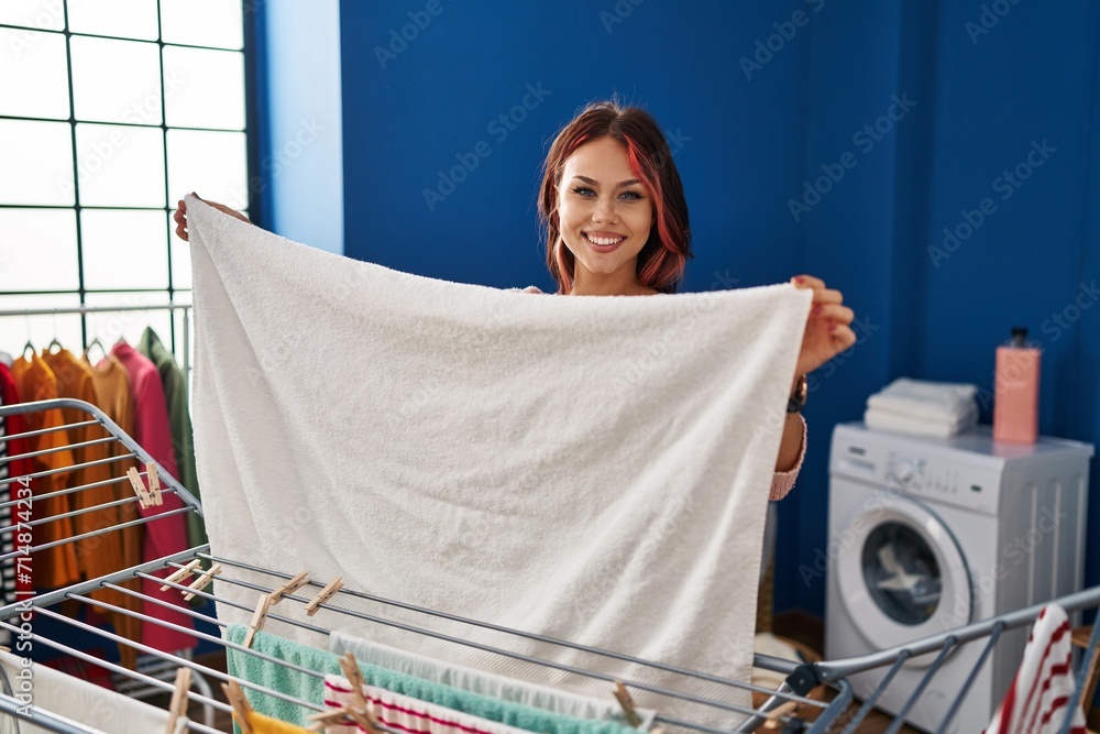 Wall mural young caucasian woman smiling confident hanging clothes on clothesline at laundry room