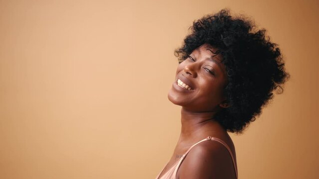 Portrait of a young African-American woman in beige lingerie posing on a beige background. The concept of skin care, cosmetology and spa treatments.